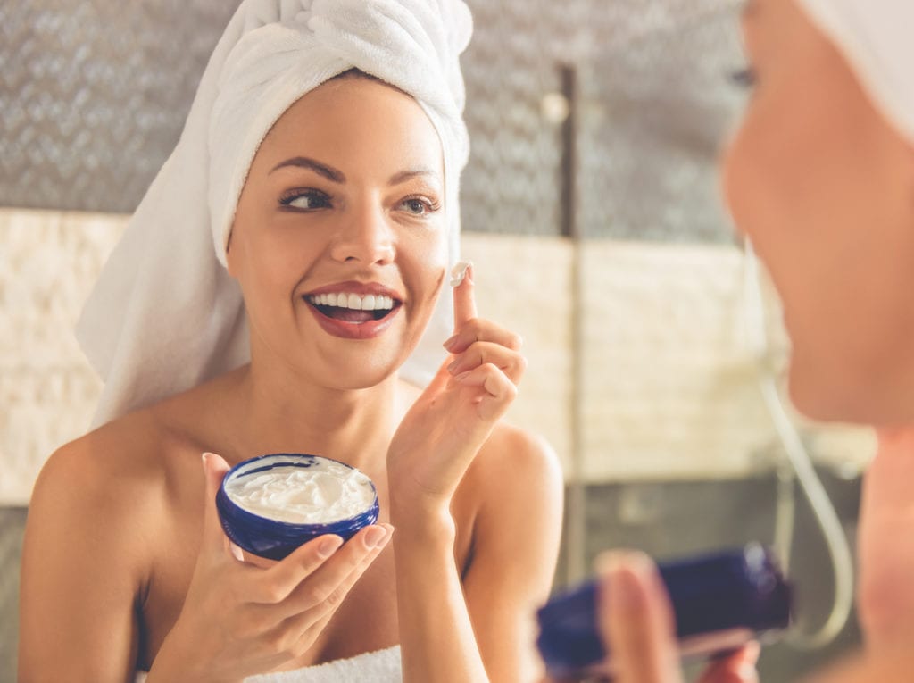 Woman applying face cream after bath