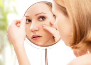 Woman looking at her face at the mirror