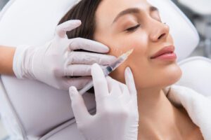 woman getting cheek filler on a close up shot with the nurses hands on her face