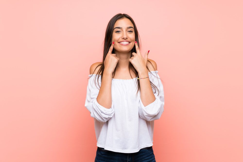 Young woman over isolated pink background smiling with a happy and pleasant expression.