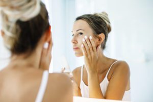 Woman looking at face in the mirror considering an IPL photofacial