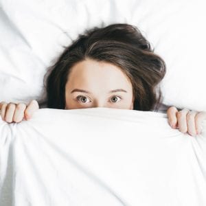 Woman covering her half face with blanket
