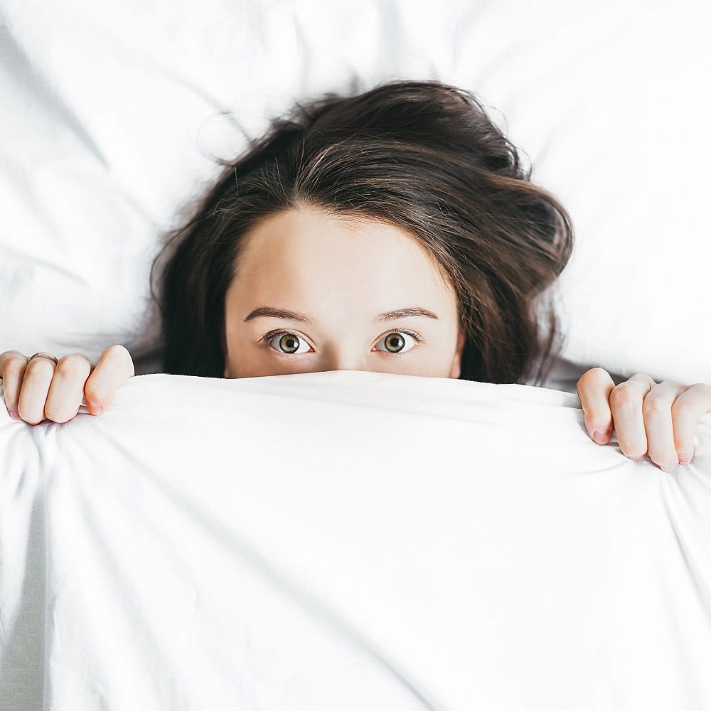 Woman covering her half face with blanket